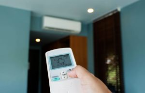 Hand,Holding,Air,Conditioner,Remote,Controller,In,Room